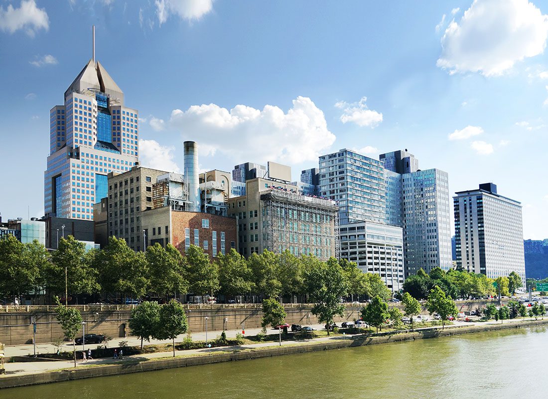 About Our Agency - Commercial Buildings by the River in Downtown Pittsburgh Pennsylvania Against a Blue Sky